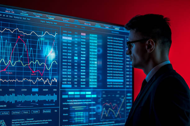 Fotografía de un hombre de traje mirando una pantalla azul con algunos datos para ilustrar artículo Datos y analítica, claves del éxito en servicios financieros: Oscar Reyes de la Campa