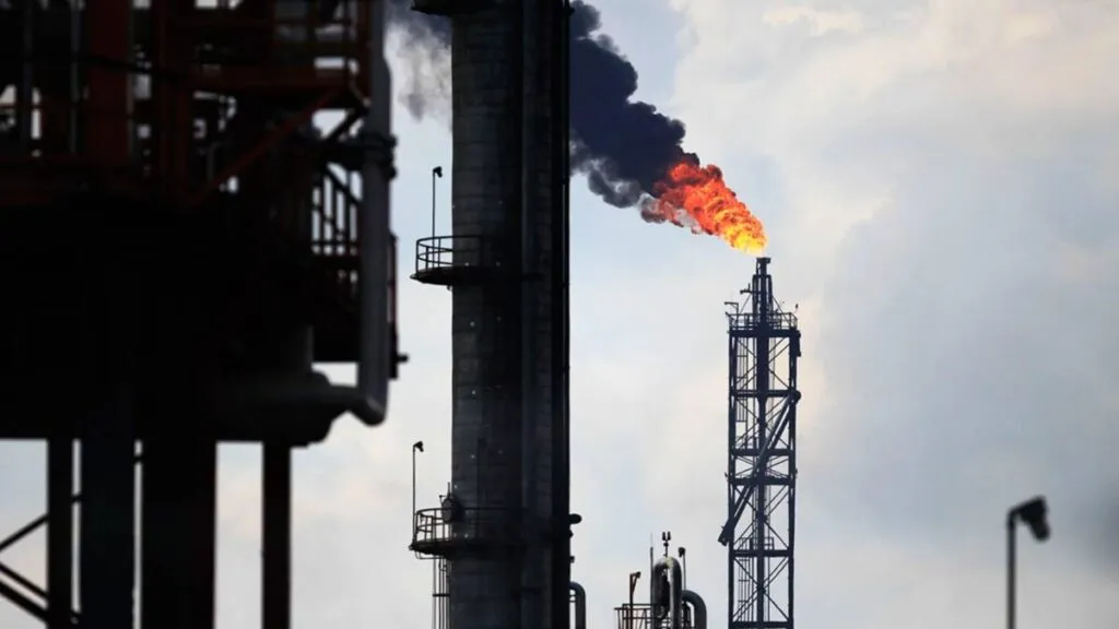 Tanques de almacenamiento de crudo y gráficas financieras reflejando la caída del precio del petróleo tras anuncio de producción de la OPEP