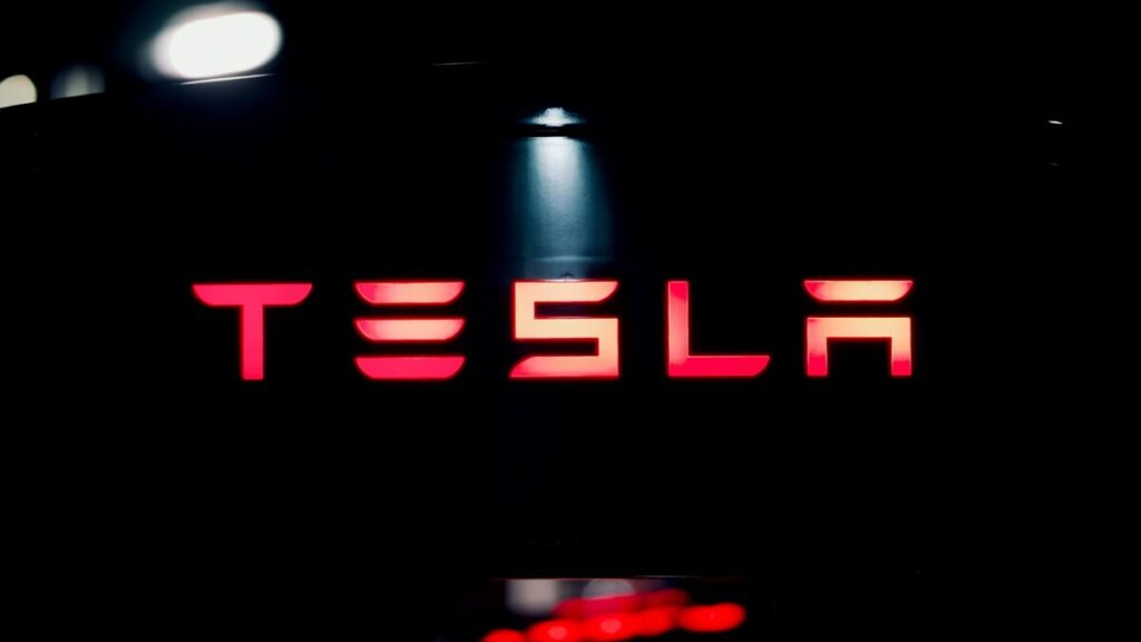 Fotografía editorial de una planta de Tesla con vehículos eléctricos en línea de producción, reflejando la caída de ganancias por mayores costos y aranceles.