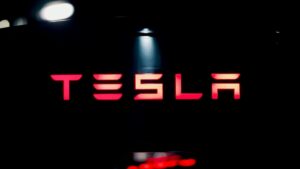 Fotografía editorial de una planta de Tesla con vehículos eléctricos en línea de producción, reflejando la caída de ganancias por mayores costos y aranceles.