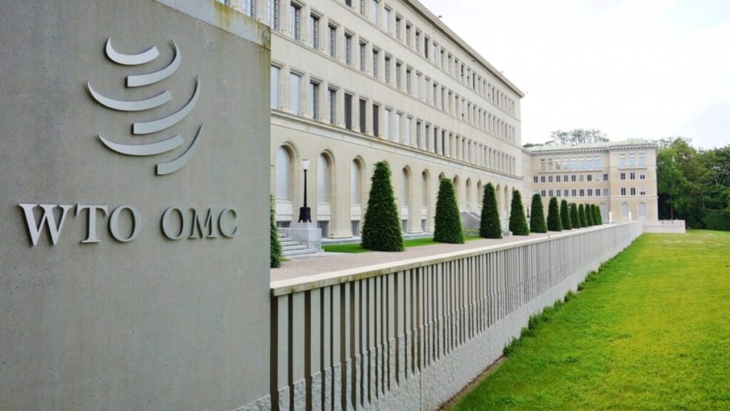 Imagen editorial de contenedores y banderas de potencias económicas reflejando el impacto global de los aranceles anticipado por la OMC en 2026