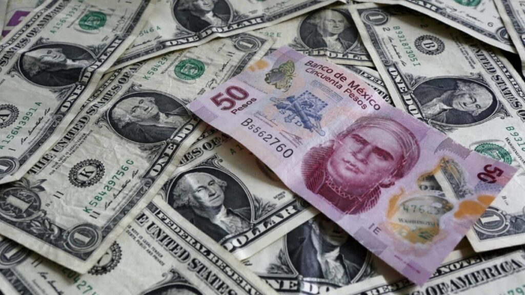 Fotografía editorial de billetes de dólar y peso mexicano en mesa de cambio, representando el fortalecimiento del dólar y la leve depreciación del peso.