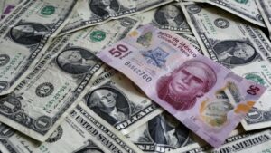 Fotografía editorial de billetes de dólar y peso mexicano en mesa de cambio, representando el fortalecimiento del dólar y la leve depreciación del peso.