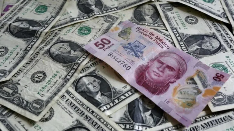 Fotografía editorial de billetes de dólar y peso mexicano en mesa de cambio, representando el fortalecimiento del dólar y la leve depreciación del peso.