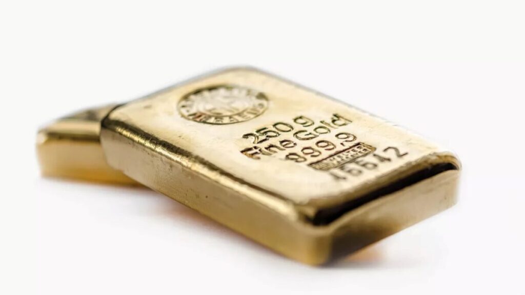 Fotografía editorial de lingotes de oro sobre fondo neutro, reflejando la caída del precio del oro por señales de distensión comercial entre EE. UU. y China.