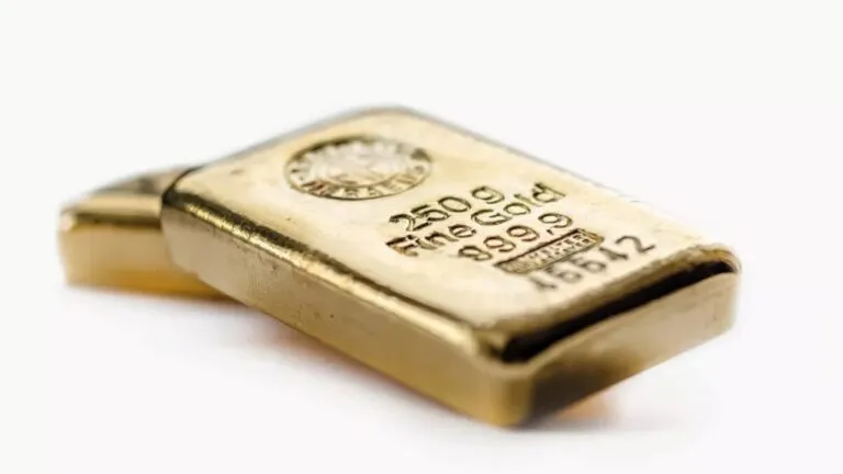 Fotografía editorial de lingotes de oro sobre fondo neutro, reflejando la caída del precio del oro por señales de distensión comercial entre EE. UU. y China.