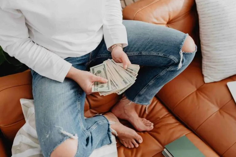 Persona contando dólares en su hogar en España bajo una lupa fiscal