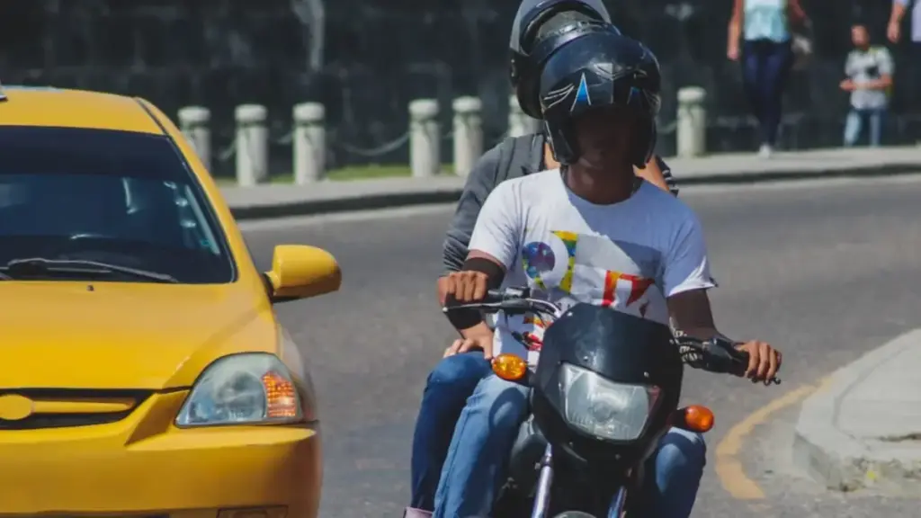 Ciudad latinoamericana con tránsito de motocicletas y actividades logísticas que ilustran la economía urbana