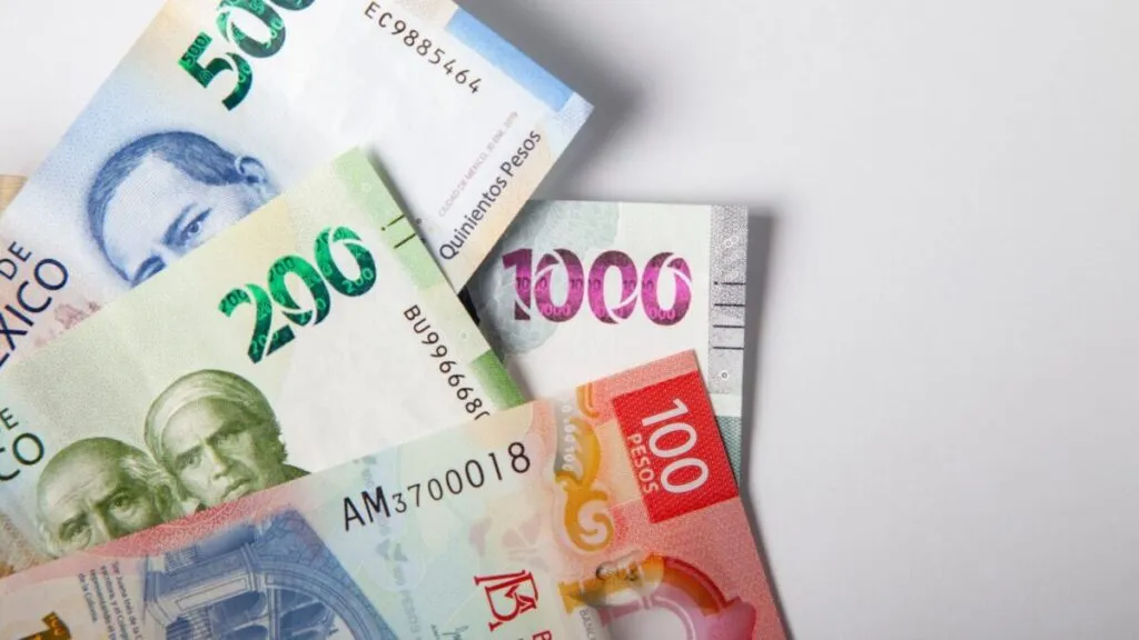 Billetes y gráficos financieros que representan el comportamiento del peso mexicano frente al dólar en una jornada de bajo volumen