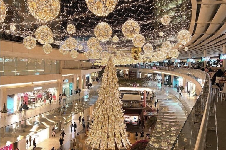 Pasillo amplio de una tienda de retail decorada para Navidad con poca afluencia de clientes, reflejando baja actividad comercial.