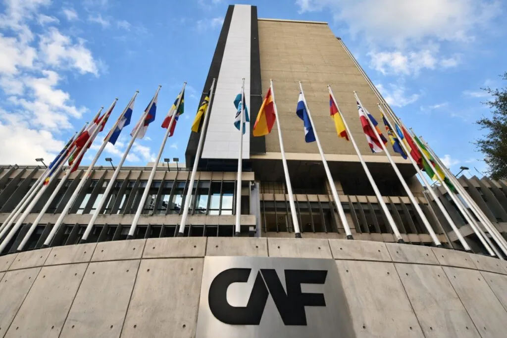 Edificio de CAF con banderas internacionales, representación institucional de foro con compradores globales