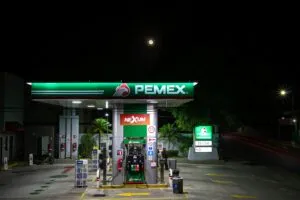 Imagen de una estación de servicio Pemex en México, con autos cargando combustible y señalética visible.