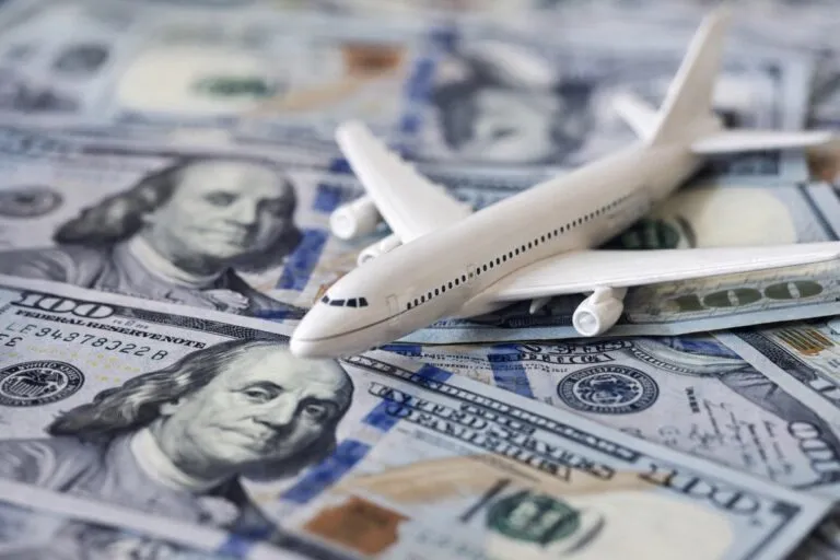 Imagen editorial que representa el déficit de divisas por turismo en Argentina, con billetes de dólares y un avión