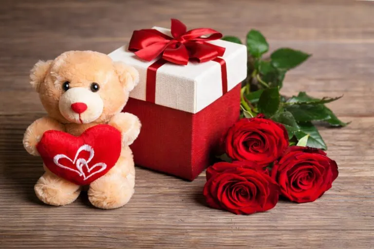 Peluche con corazón, caja de regalo roja y rosas sobre una mesa, imagen representativa del 14 de febrero