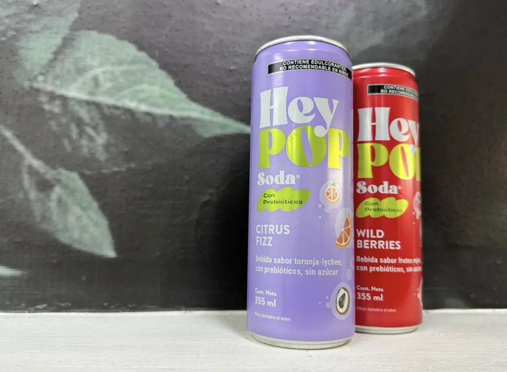 Latas de HeyPOP bebida prebiótica en sabores Wild Berries y Citrus Fizz.