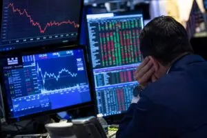 Analista financiero observa pantallas con gráficos bursátiles y datos de mercado mientras evalúa el impacto de riesgos geopolíticos en la economía global.