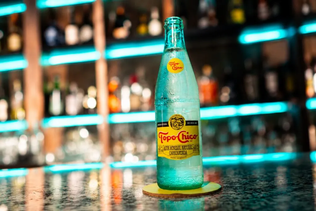 Botellas de agua mineral Topo Chico que representan la reactivación de su distribución en Texas por parte de Coca-Cola.
